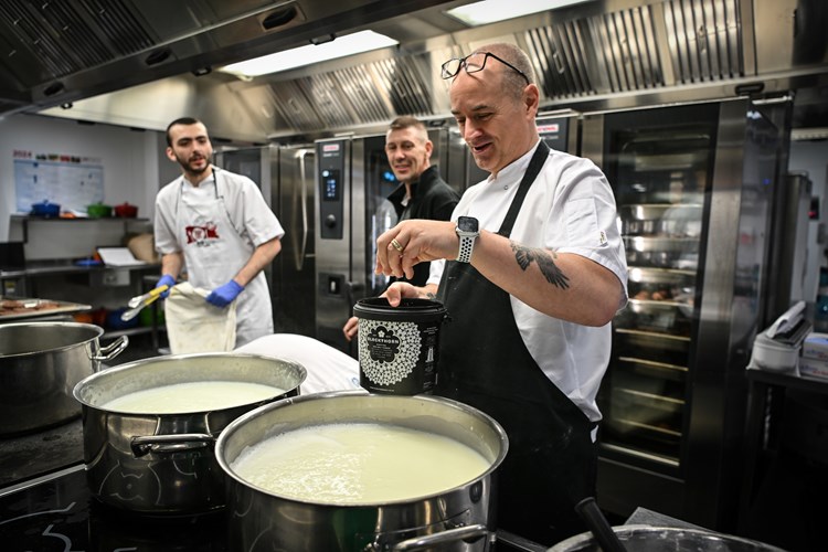 A chef seasoning a white sauce