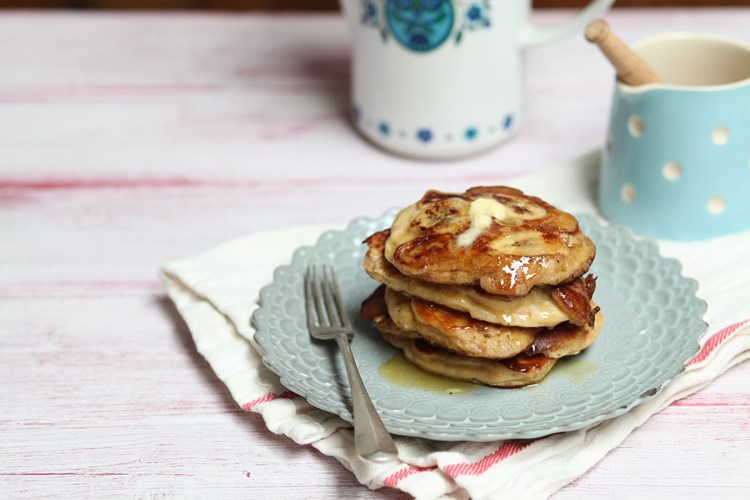 a stack of pancakes on a plate, drizzled with maple syrup