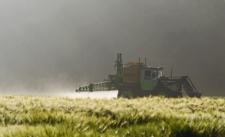 Tractor spraying onto field