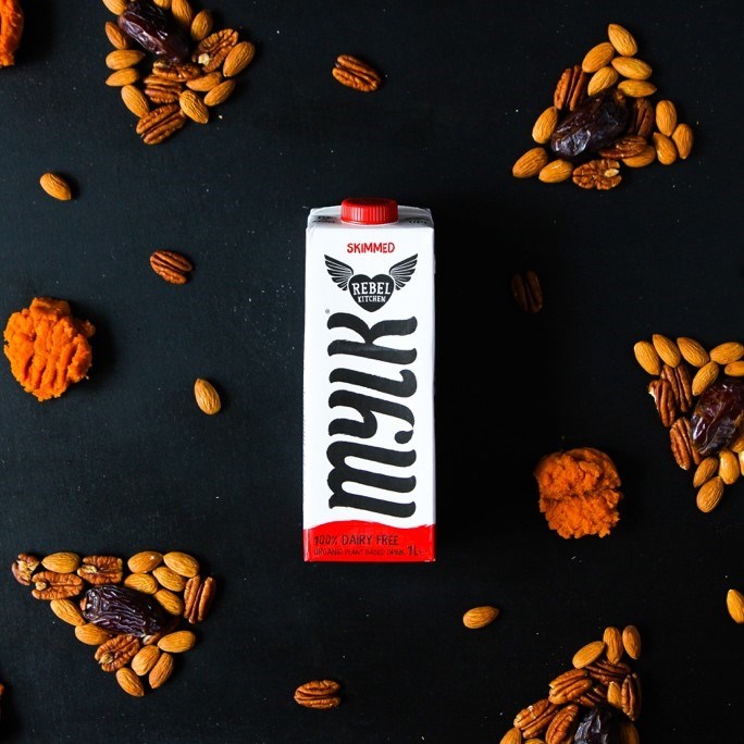carton of rebel kitchen milk surrounded by pie-shaped arrangements of nuts, dates and pumpkin