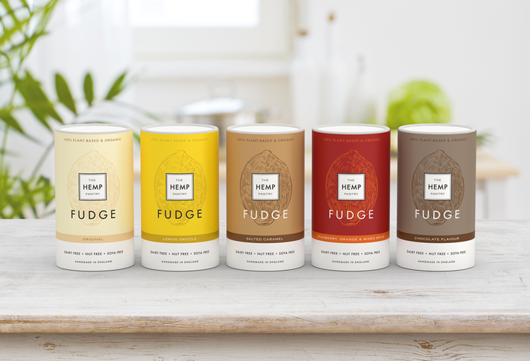 A photo of The Hemp Pantry's fudge tubs on a white stained wooden table with plants in the background