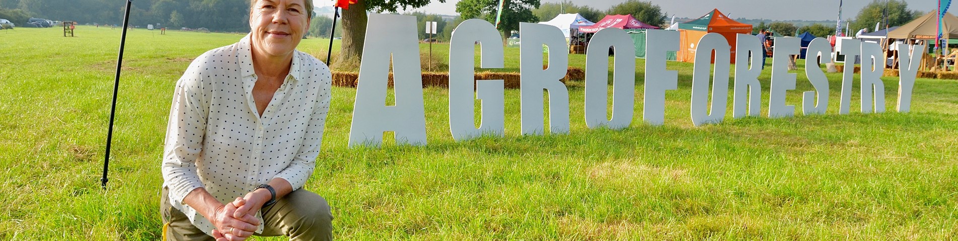 AFS23 - Helen Browning on knee in front of agroforestry show signcreditPeteWilliams.jpg