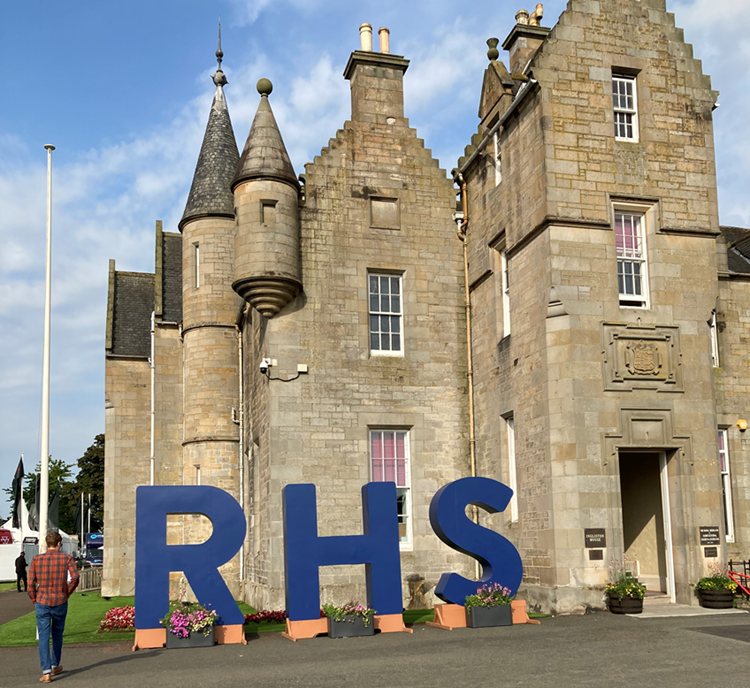 Blue eight foot letters "RHS" outside old sandstone building. 