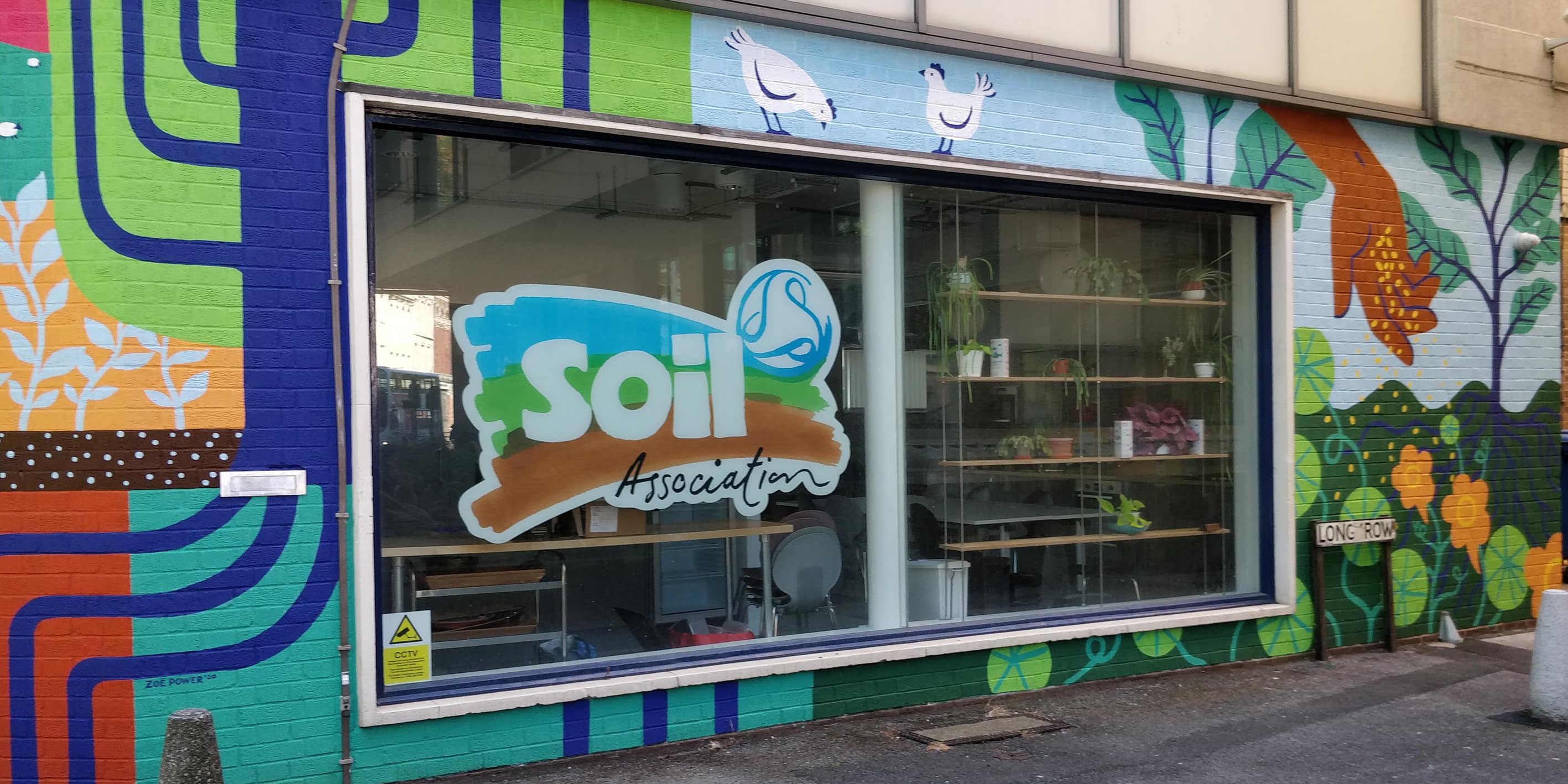 Shop front with Soil Association logo on the window and brightly coloured painted brickwork. 
