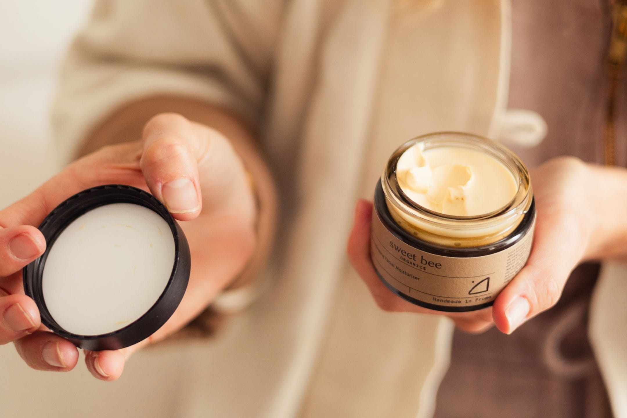 Person holds an open jar of moisturiser