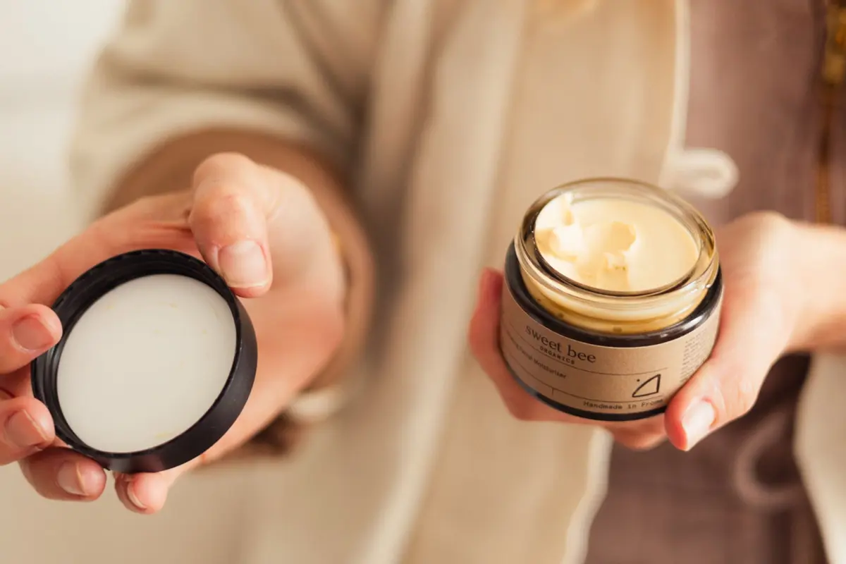 Person holds an open jar of moisturiser