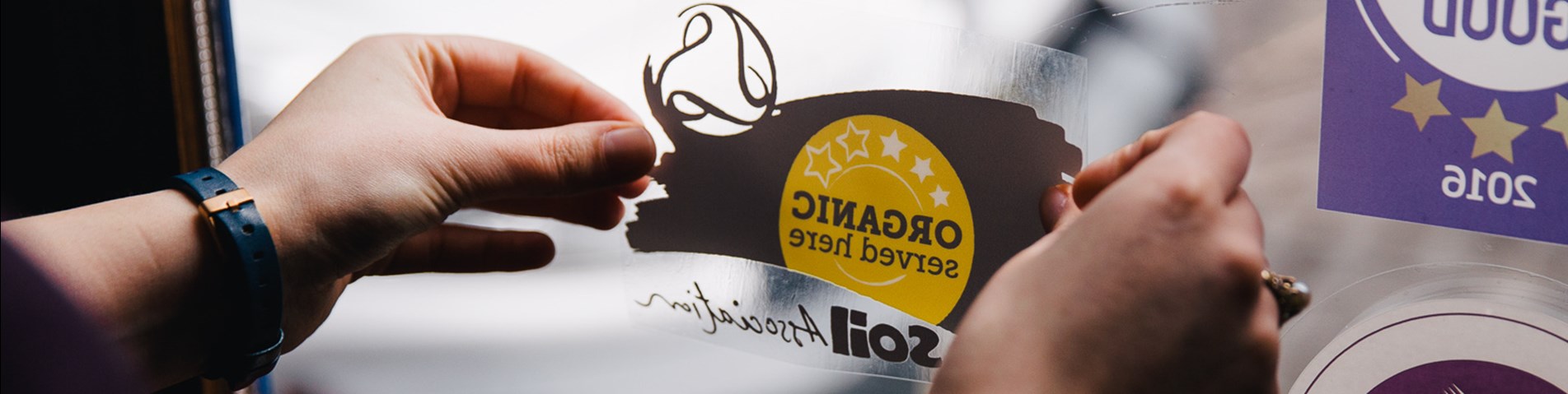 Organic Served Here logo being placed in window