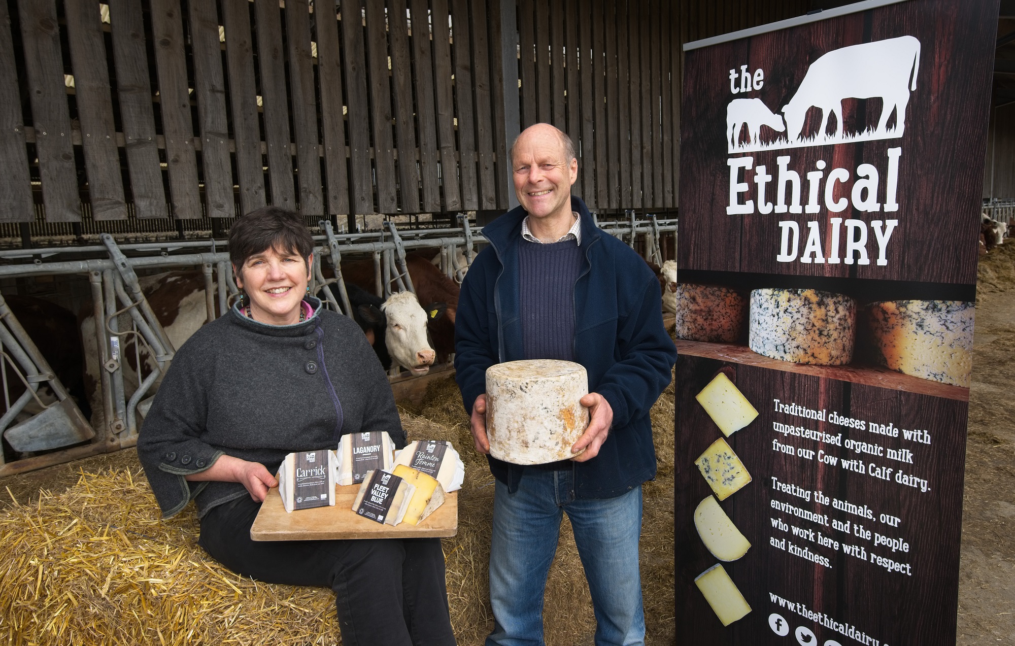 Wilma and David from Finlay cheese pose in front of a cow shed with some of their products. 