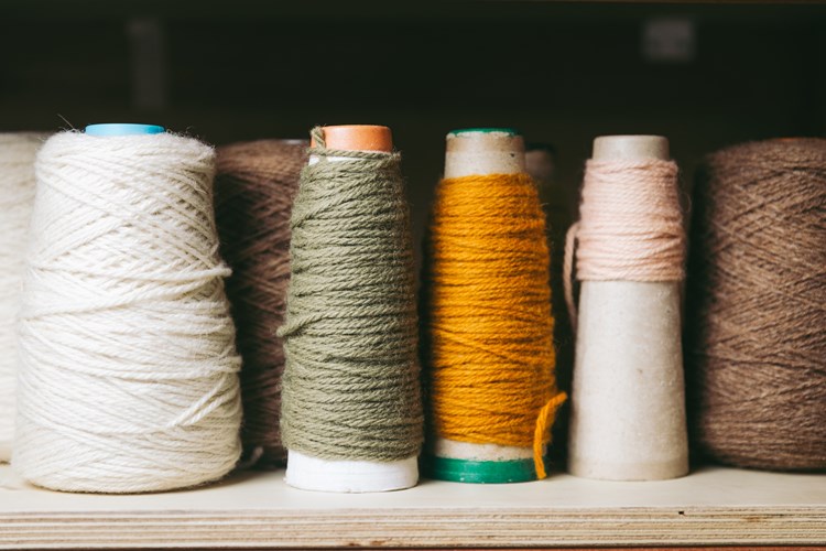 A wooden shelf of yarn spools of various colours