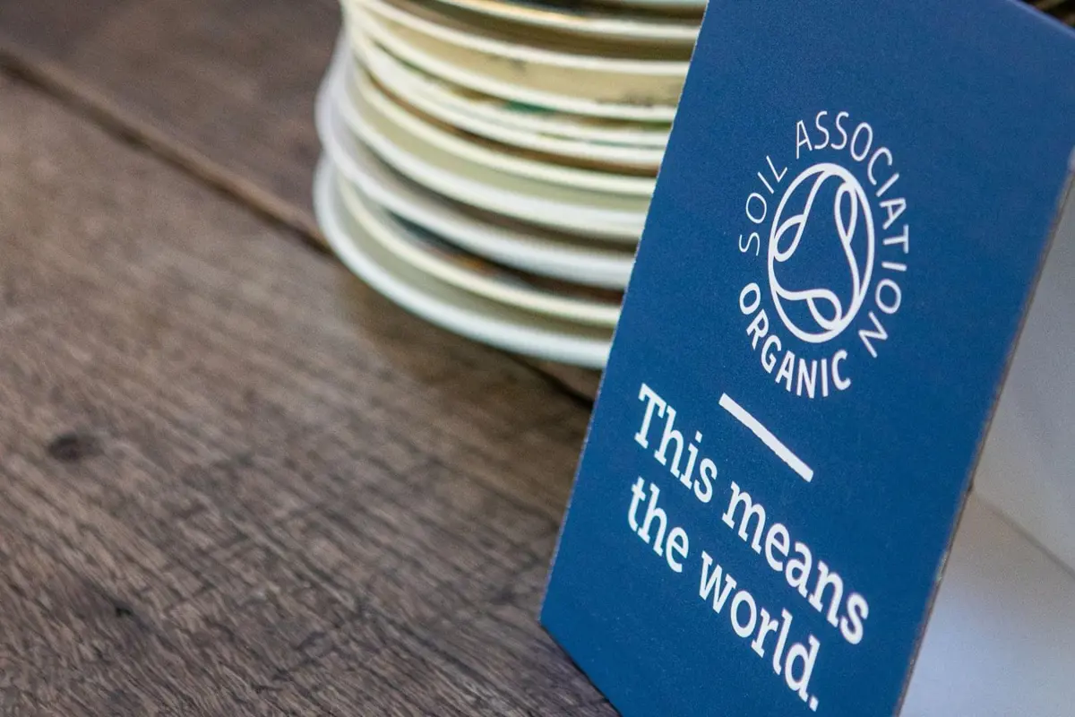 A stack of side plates on a wooden table next to a Soil Association Organic sign
