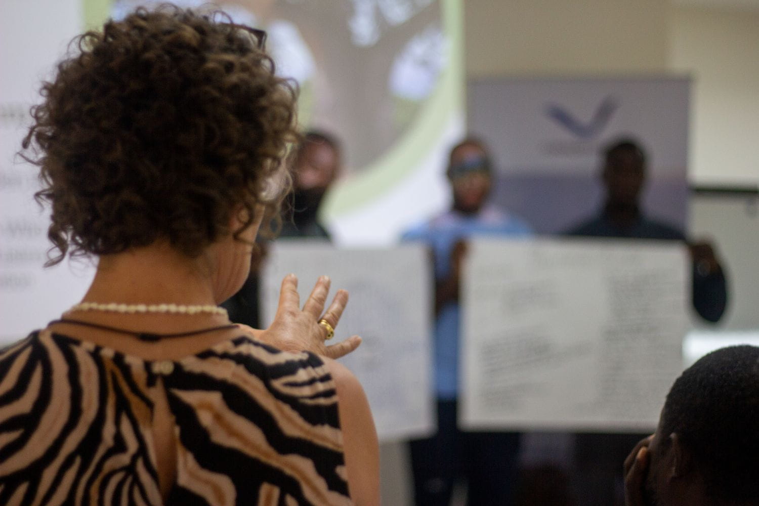 A woman providing feedback to a group of course delegates, who are presenting their work for review