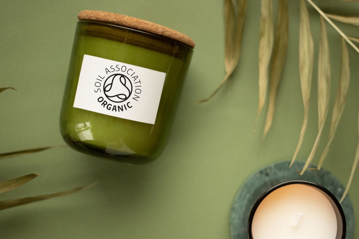 Two candles with glass jars and cork lids, bearing the Soil Association organic symbol