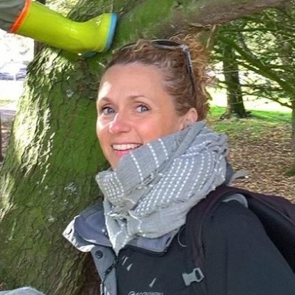 A woman smiling in a wooded area