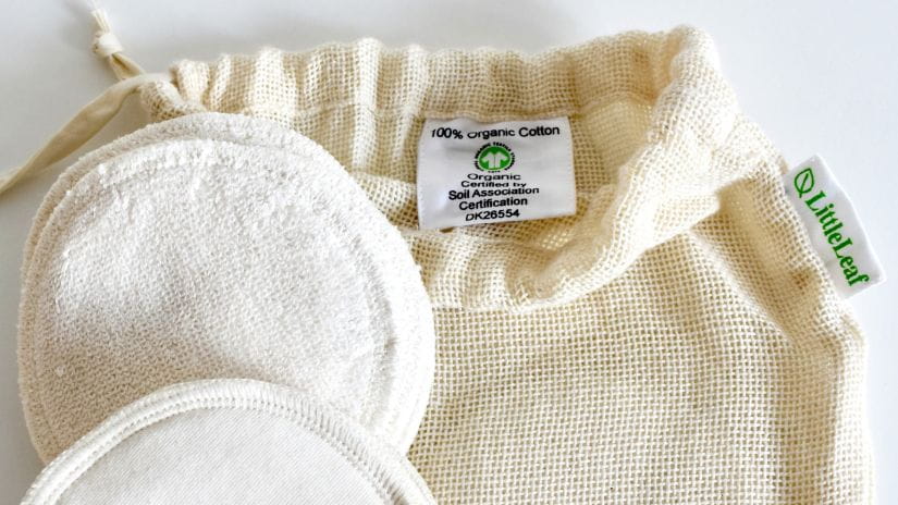 Organic cotton makeup remover pads with GOTS logo displayed in the drawstring bag
