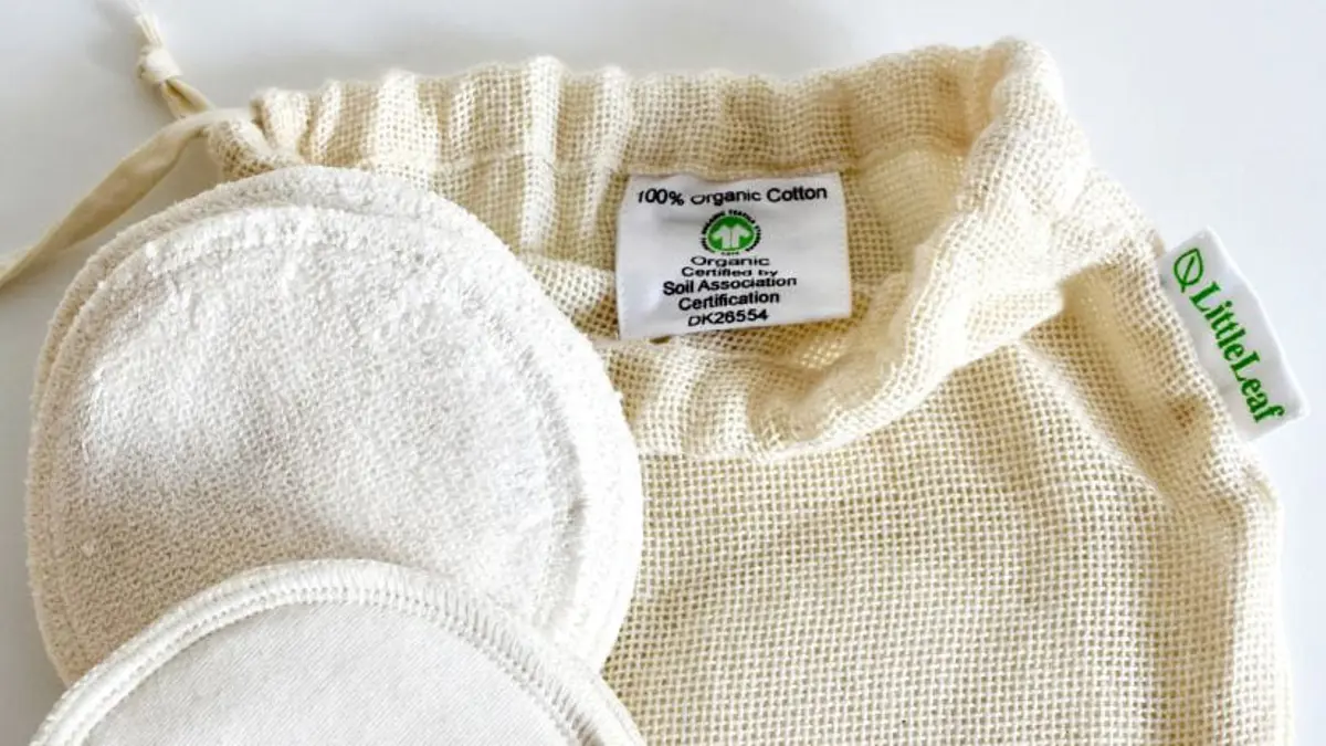 Organic cotton makeup remover pads with GOTS logo displayed in the drawstring bag