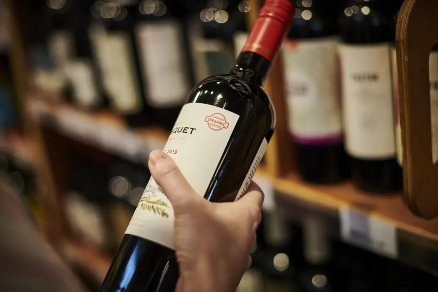 A hand holding a bottle of red wine