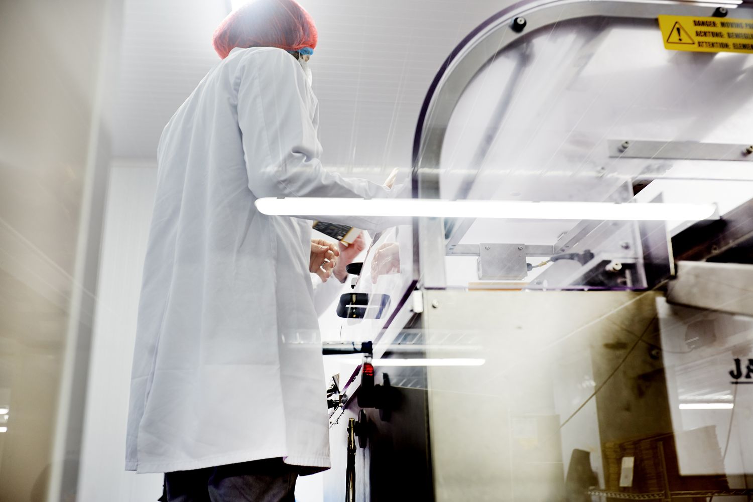 Person wearing a protective white coat and hair net in a lab environment
