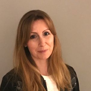 A woman with long hair wearing a white shirt and black blazer