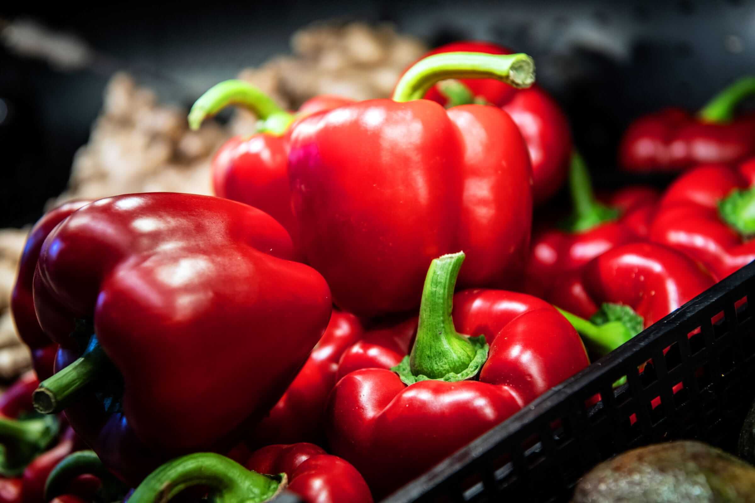 A display of fresh organic red bell peppers in the produce section of an independent store