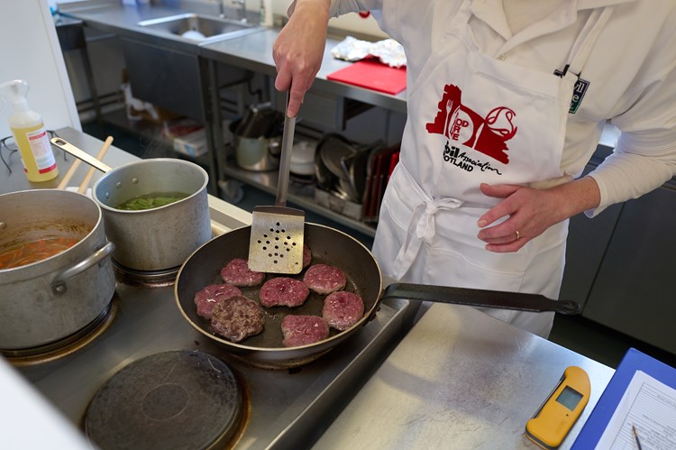 a chef wearing an apron and cooking burgers in an industrial kitchen