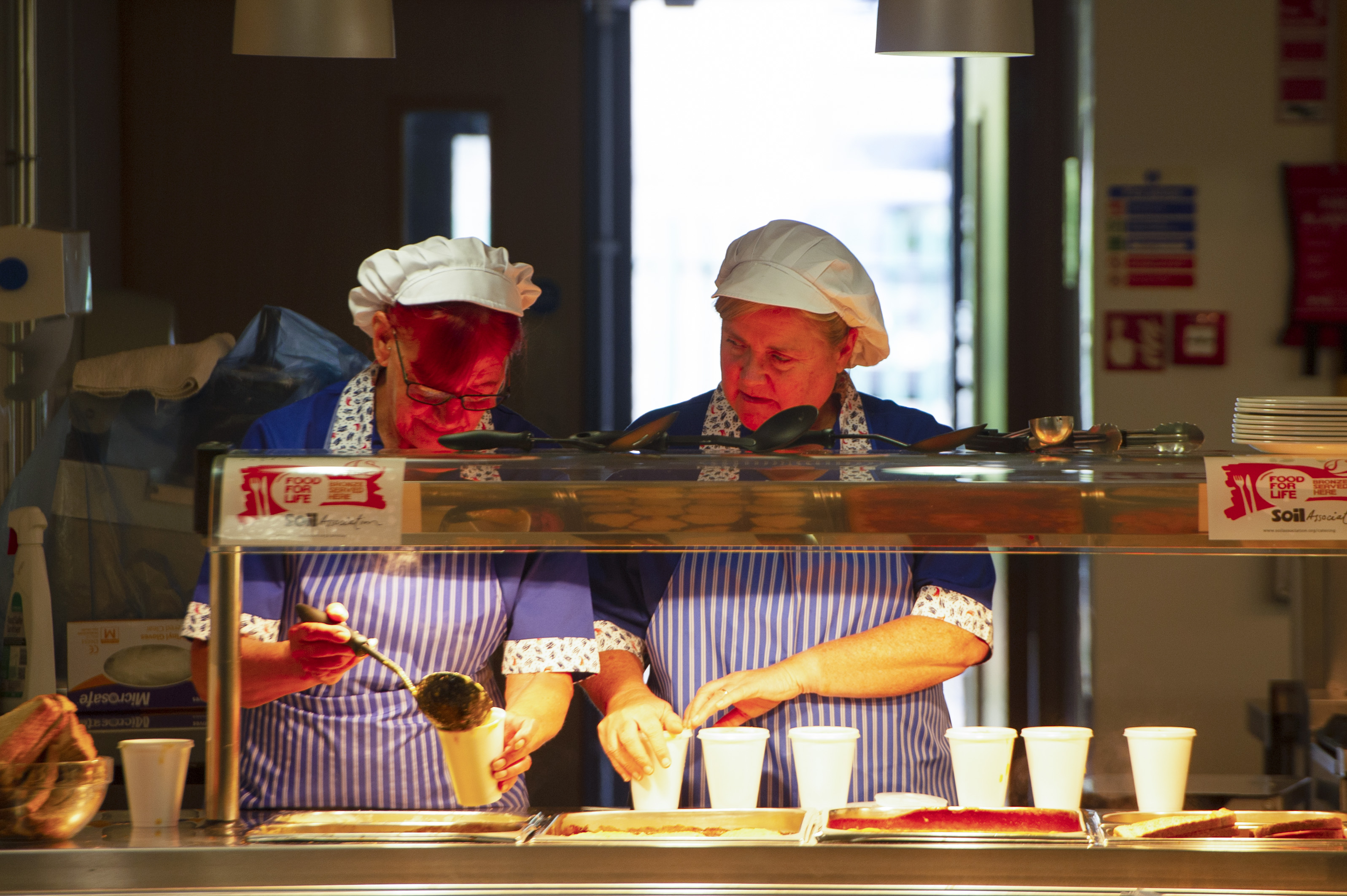 Two caterers serving cups of soup