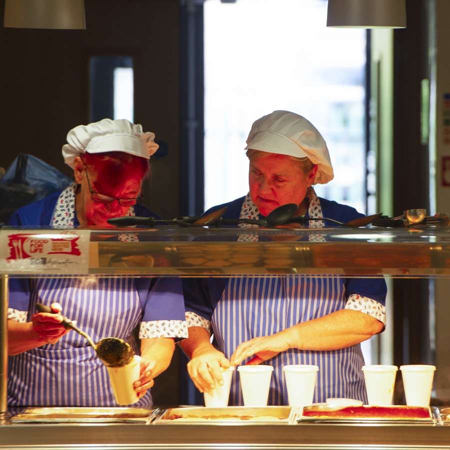 Two caterers serving cups of soup