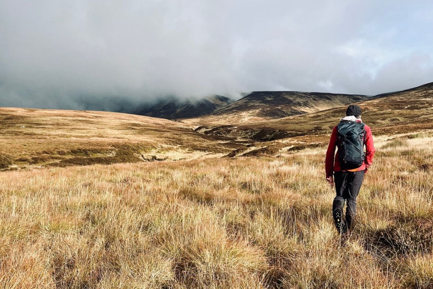 A person with a backpack walking in rugged terrain
