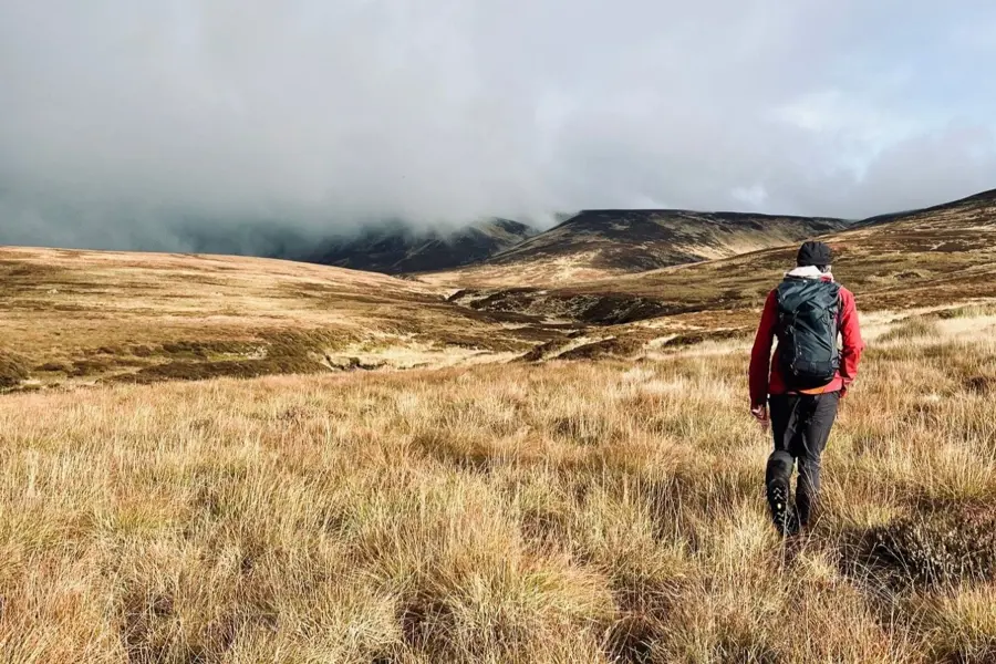 A person with a backpack walking in rugged terrain