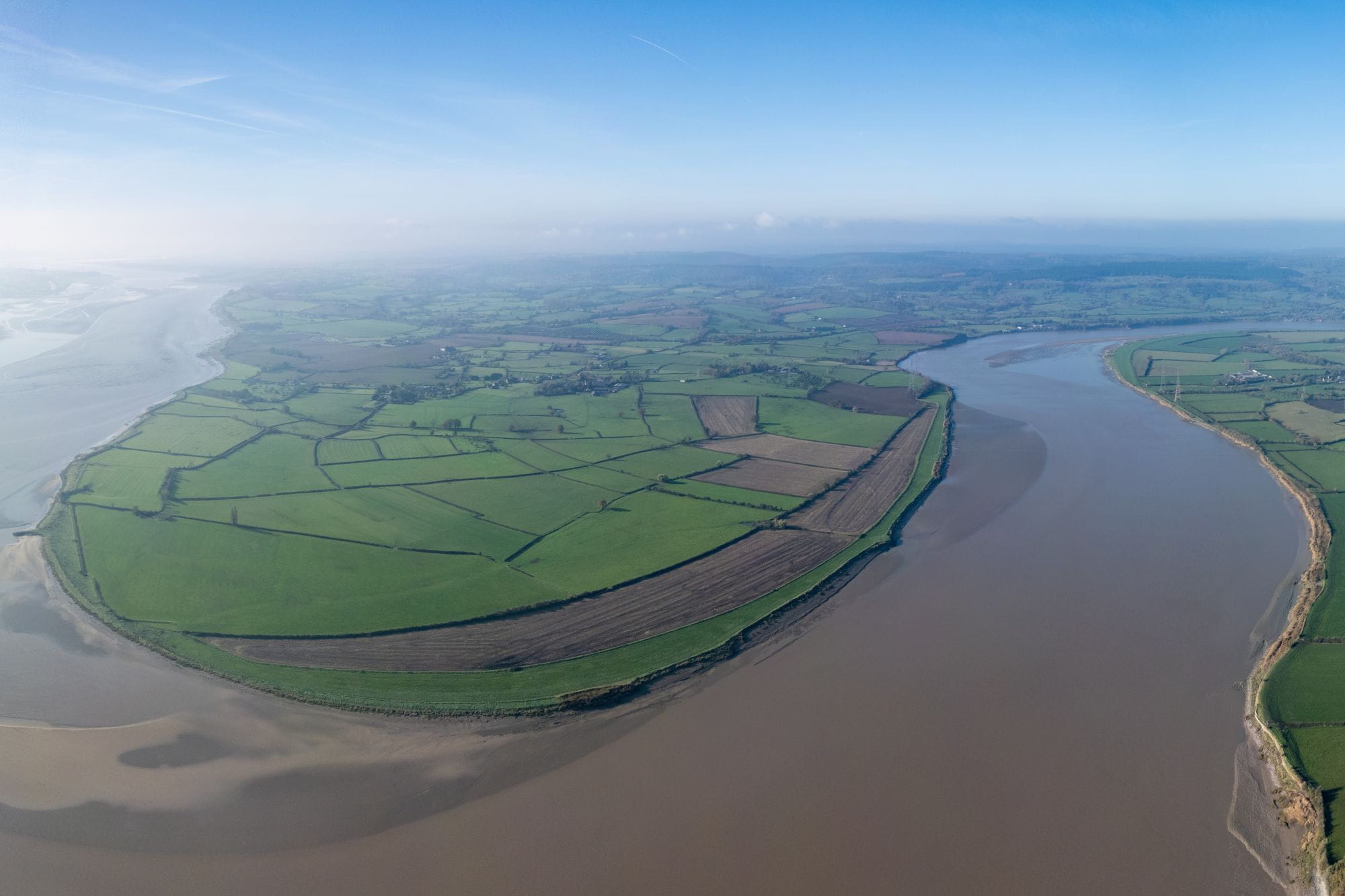 An aerial photo of a saltmarsh landscape, with fields surrounded by a meandering river