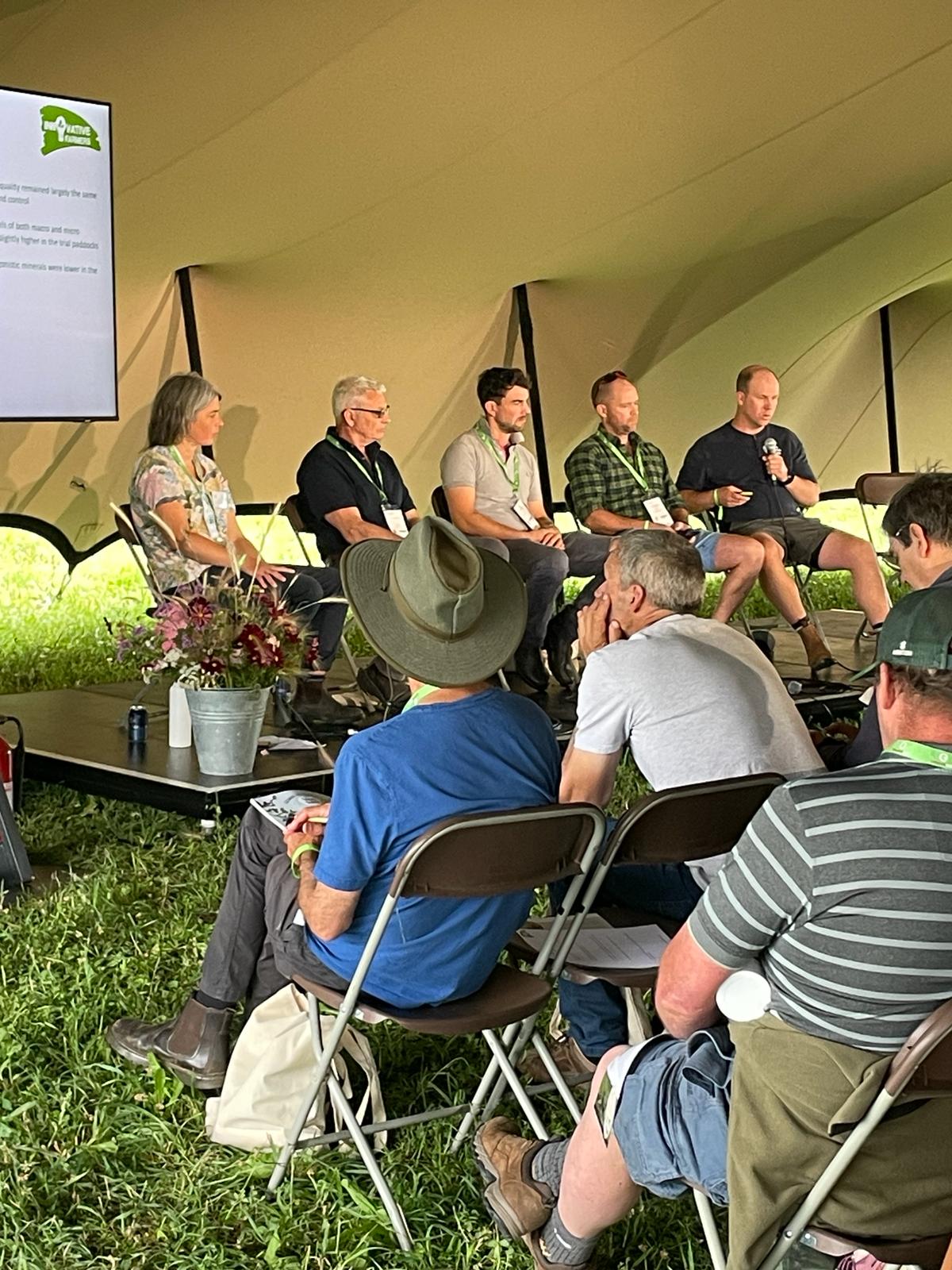 Speakers delivering a session, held in a tent in front of an audience