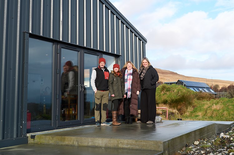 a group of people standing outside a modern barn