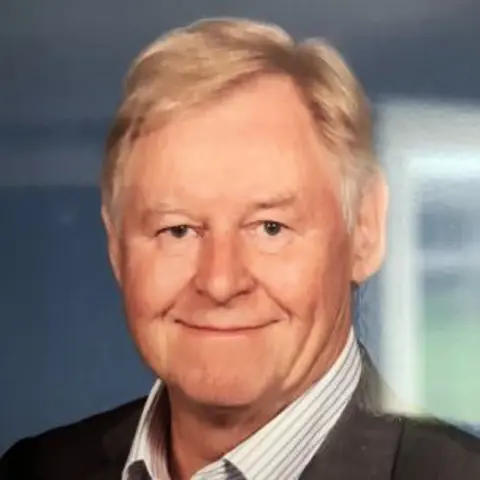 Smiling man in a sit with sandy hair