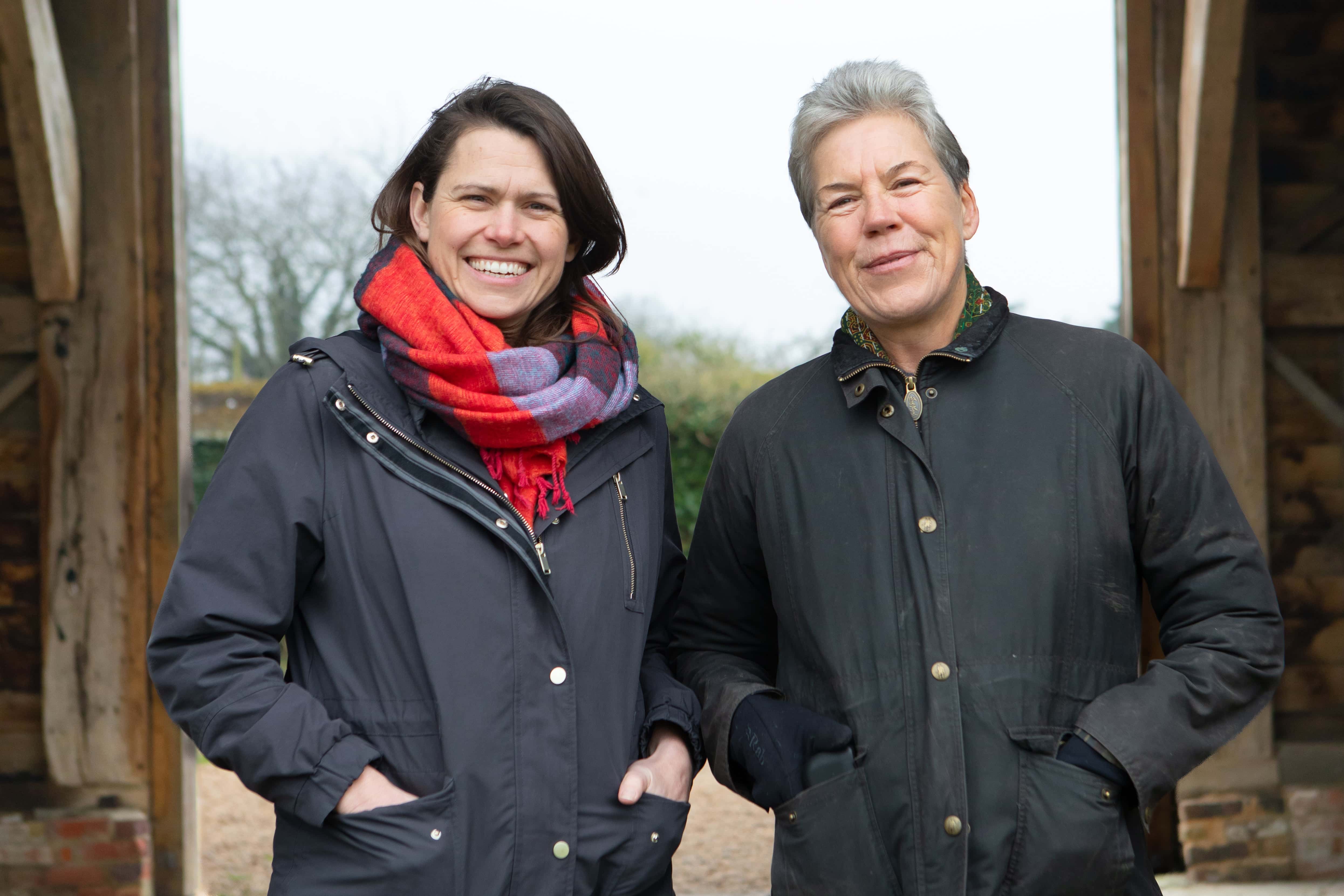 Two people in outdoor clothing stand smiling at camera. 