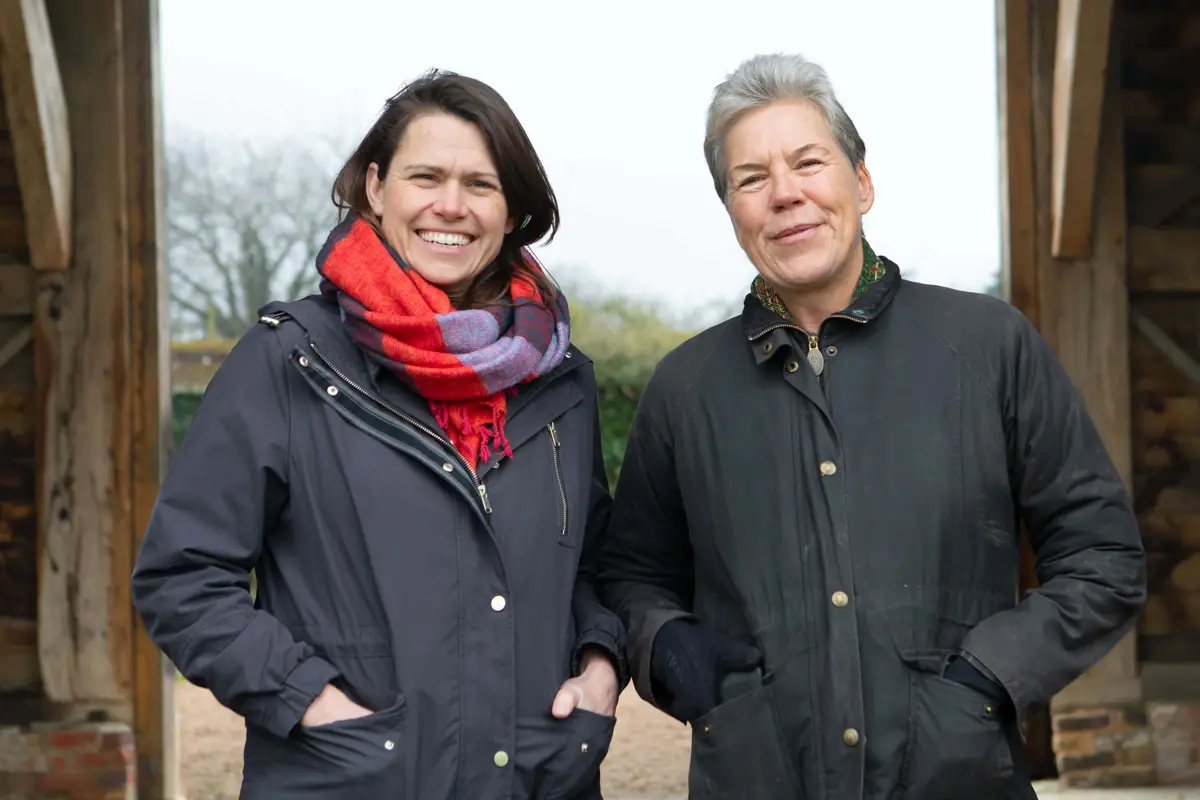Two people in outdoor clothing stand smiling at camera. 