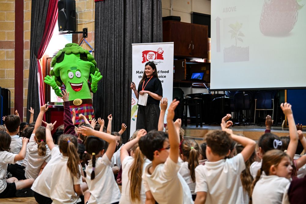 Healthy eating mascot Broccoli Bill waves to pupils at a primary school assembly in Falkirk